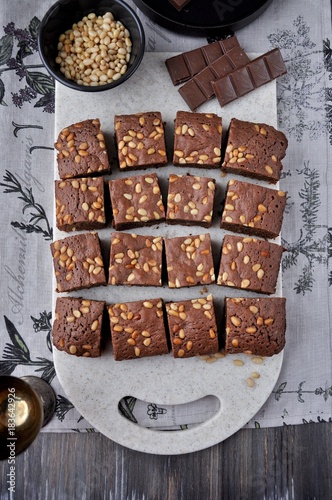 Brownie with pine nuts on a cutting board. View from above. Rustic style
