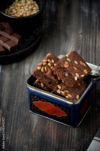 Brownie with pine nuts. Dark background. Rustic style