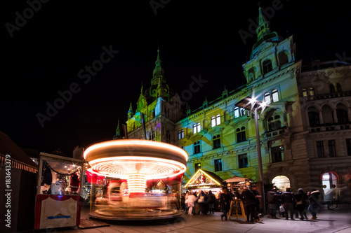 Spinning carousel on christmas fair in Graz with town hall