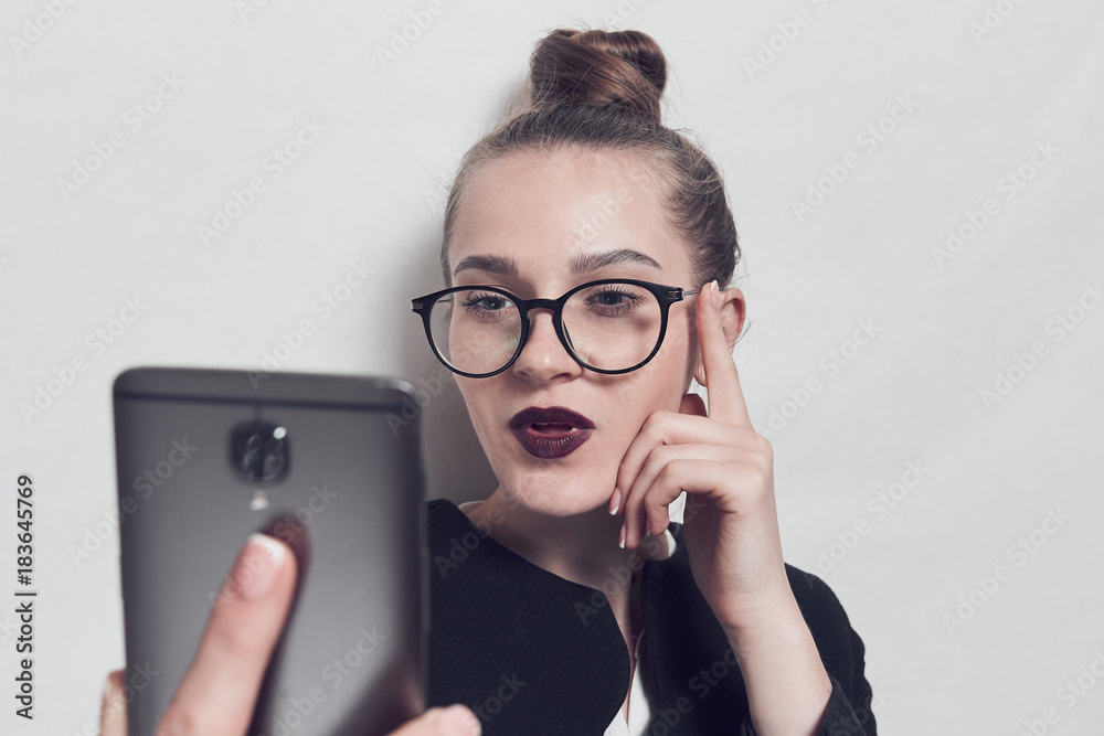 Businesswoman does selfie. The girl in black glasses. Smartphone in hand. Businesswoman does selfie. The girl in black glasses. Smartphone in hand.