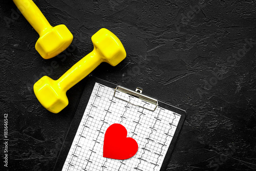 Prevent heart disease. Heart sign, cardiogram and dumbbells on black background top view copyspace photo