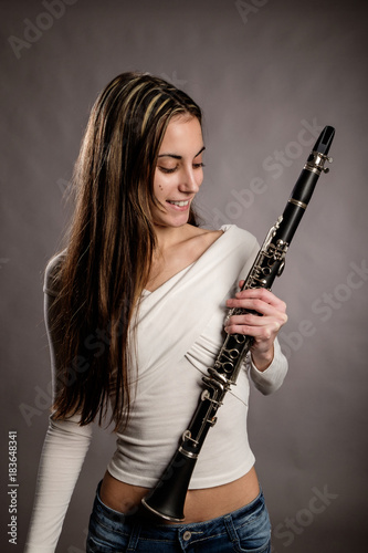 young woman holding a clarinet on a gray background