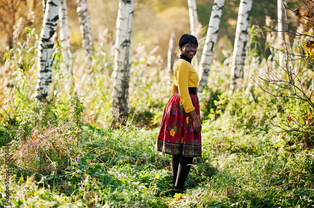 African american girl at yellow and red dress at golden autumn fall park. African american girl at yellow and red dress at golden autumn fall park.