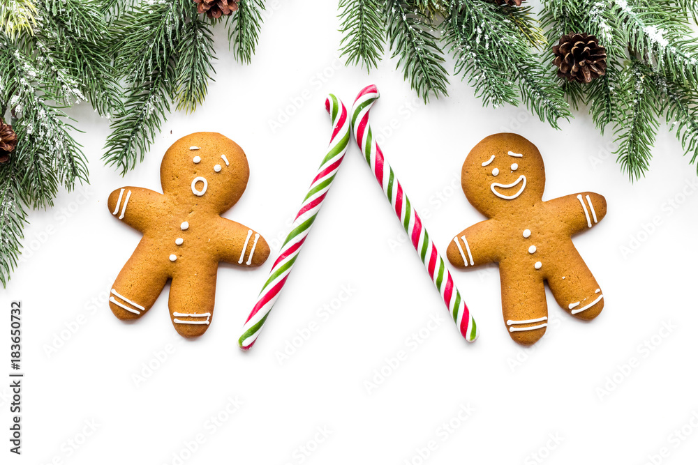 Gingerbread man cookies for New Year meal near spruce branch on white background top view Gingerbread man cookies for New Year meal near spruce branch on white background top view