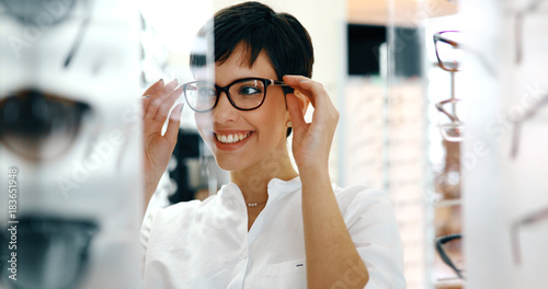 Beautiful woman with optician trying eyeglasses photo