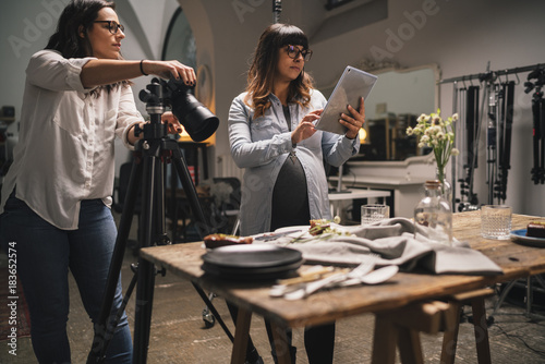 Pregnant woman with a colleague working on a food photoshoot in a studio photo