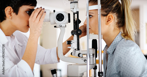 Canvas-taulu Attentive optometrist examining female patient on slit lamp