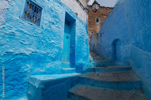 Traditional moroccan courtyard in Chefchaouen blue city medina in Morocco, architectural details in Blue town Chaouen. Typical blue walls and colorful flower pots. © sefoma