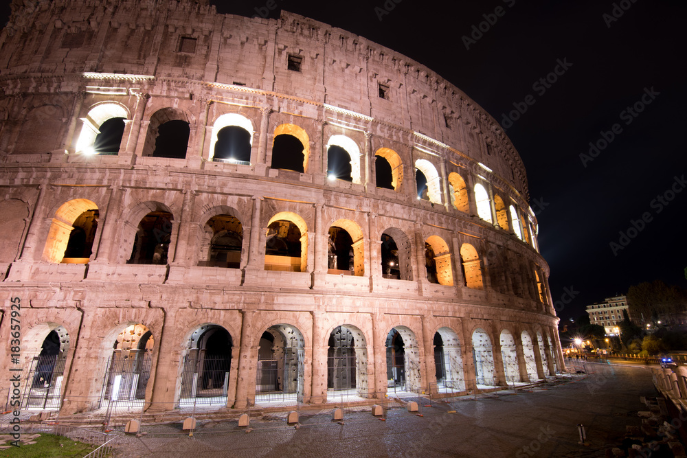 A police car patrols past the Colosseum at night
