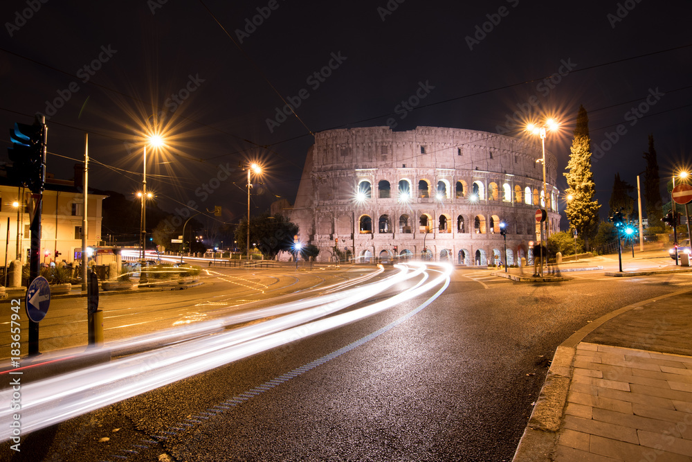 City traffic passes by the Colosseum at night