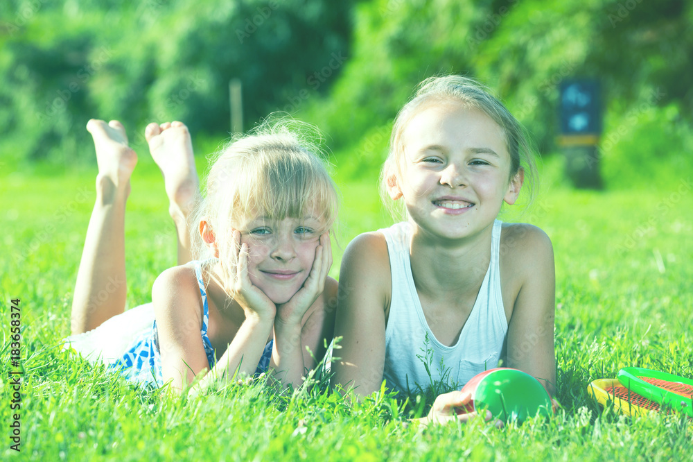 Fototapeta premium Two happy girls laying on grass