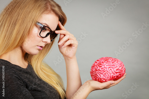 Woman thinking and holding fake brain