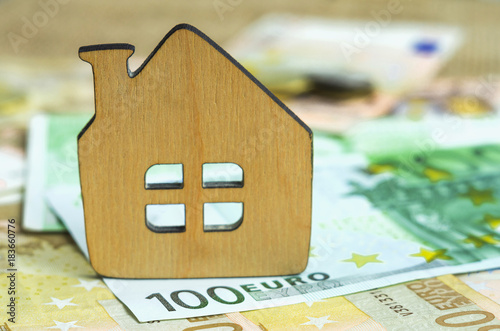 Small wooden house on the background of Euro banknotes. Symbolic image of buying or renting a house. Selective focus. photo