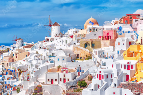 Incredible traditional white and colorful Greek architecture with fascinating wind mills on Santorini volcano Cyclades Caldera island in warm waters of Aegean sea in Greece.