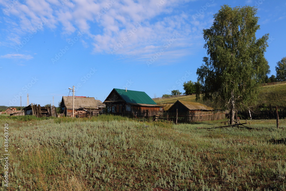 Very old wooden houses in the remote Russian village in the summer against a blue sky