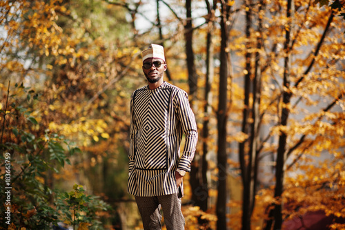 Portrait of stylish black african american man at hat and sunglasses against sunny autumn fall background.