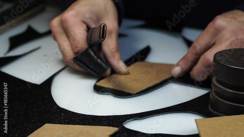 Cutting out of leather with a special knife of the sizes under a pattern - manufacturing of original leather footwear. photo