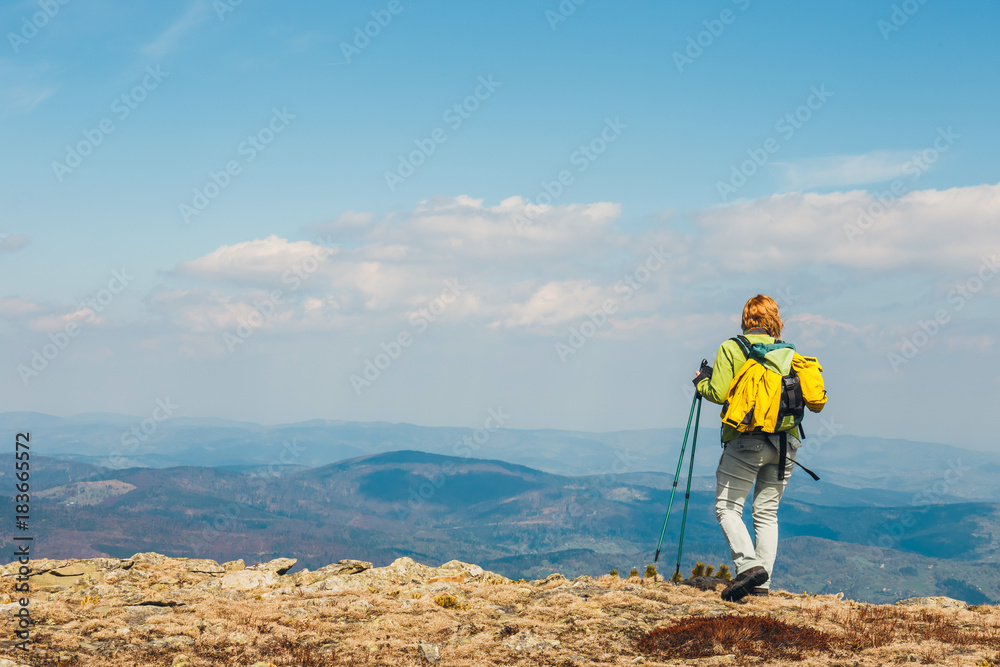 woman stands on the path and looks at the tops of mountains