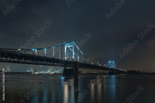 Nightshot Of Spotlighted Historical Iron Bridge across the River Rhine at Krefeld Uerdingen View To Duisburg