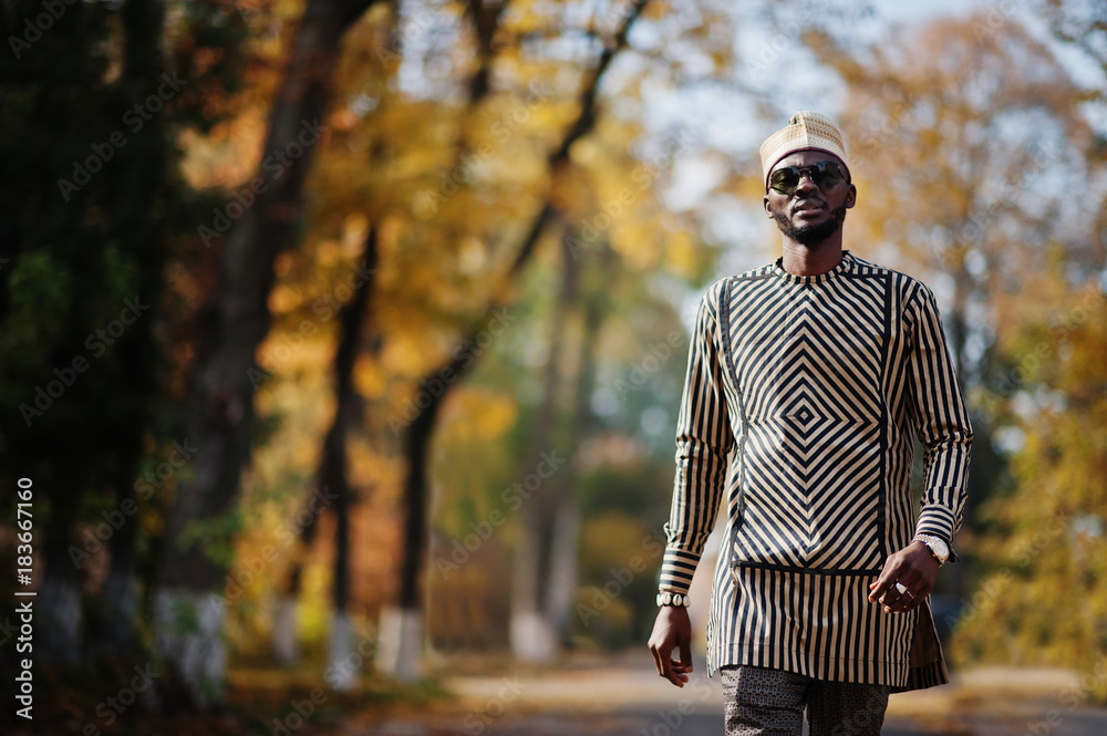 Portrait of stylish black african american man at hat and sunglasses against sunny autumn fall background. Rich people in africa at traditional dress. Portrait of stylish black african american man at hat and sunglasses against sunny autumn fall background. Rich people in africa at traditional dress.