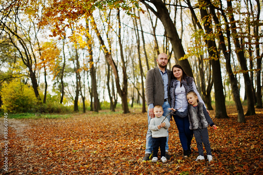 Naklejka premium Happy caucasian family of mom dad and little girl with boy at majestic autumn fall forest.
