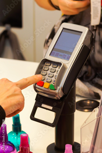 the girl enters the pin code on the terminal to pay for purchases in store