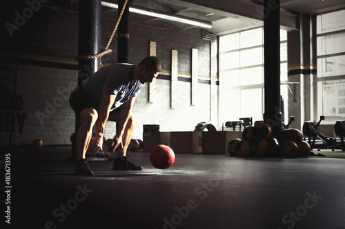 Man training with heavy medicine ball in gym photo