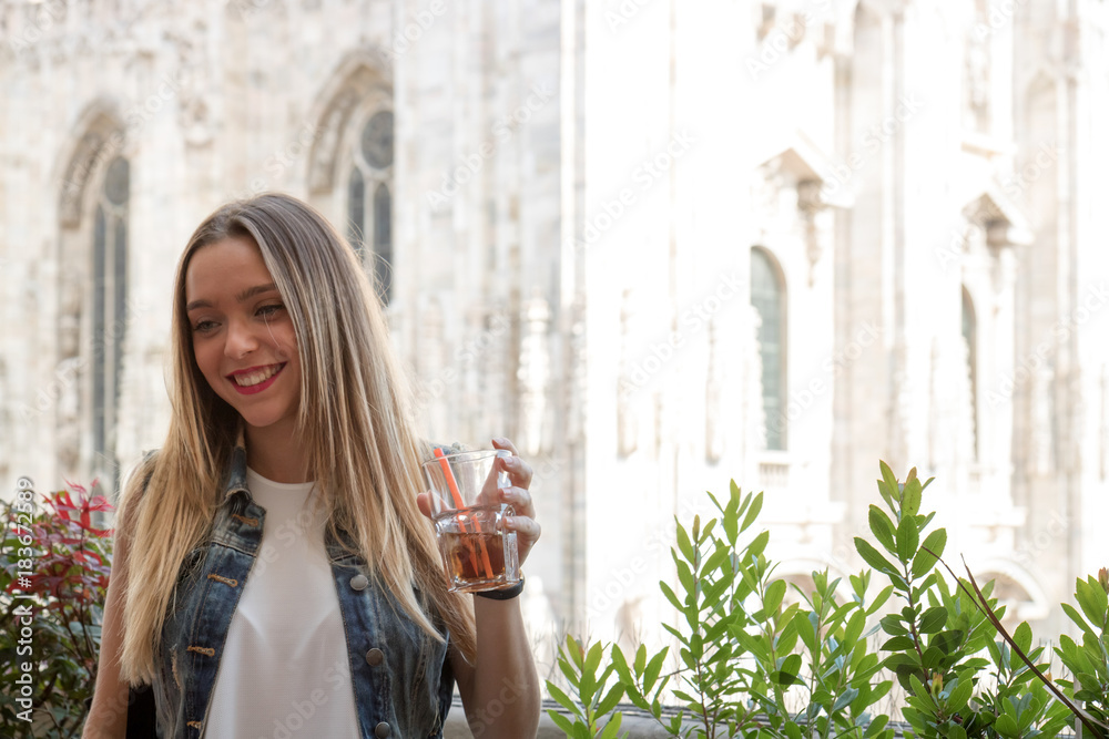 Happy young girl drinking a cocktail outdoor, during a sunny summer day. Photo taken in Milan, Italy
