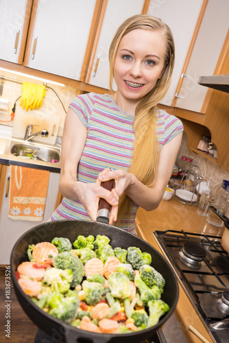 Woman cooking stir fry frozen vegetable on pan