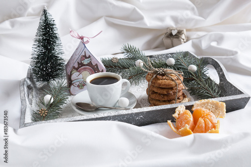 Christmas Breakfast in bed on a tray with snow, gifts, fir-tree and tangerines.