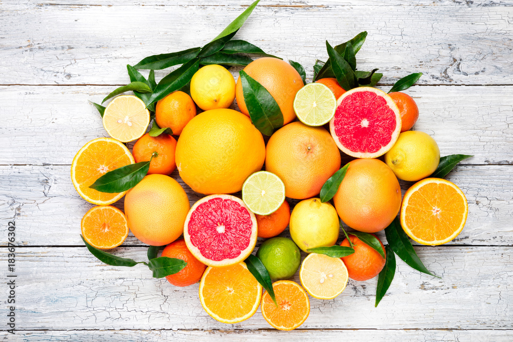 Fresh citrus fruits background. Orange, grapefruit, lemon, lime, tangerine. Mix citrus fruits with leaves. Top view