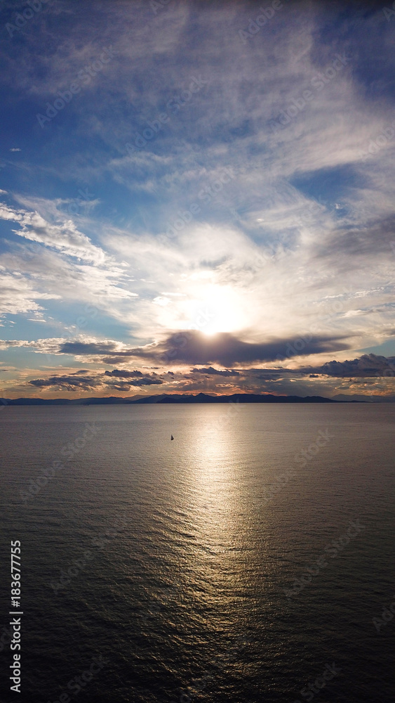 Aerial drone bird's eye view of sunset in famous coast of Voula with beautiful scattered clouds, Athens riviera, Attica, Greece