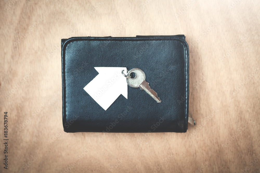 Wallet with house and key on a wood background.