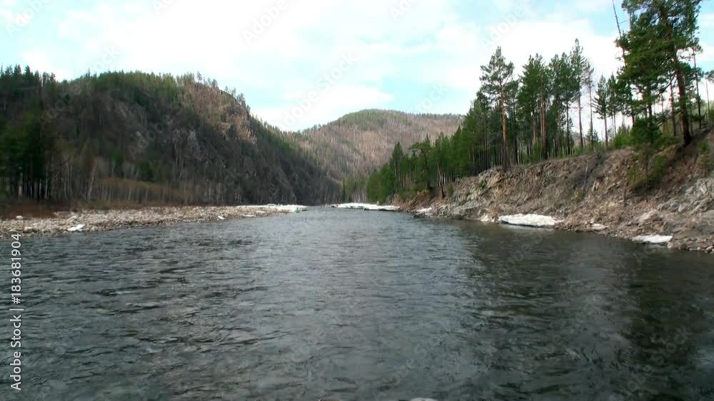 Bank of mountain river Temnik. Clean water and stone rock bottom in spring. Border of Baikal State Nature Biosphere Reserve. Ecotourism in Siberia of Russia. Bank of mountain river Temnik. Clean water and stone rock bottom in spring. Border of Baikal State Nature Biosphere Reserve. Ecotourism in Siberia of Russia.