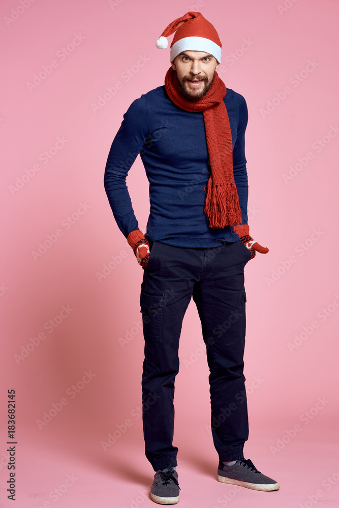 man stands full-length, hands in pockets, christmas clothes, new year, christmas, light pink background man stands full-length, hands in pockets, christmas clothes, new year, christmas, light pink background