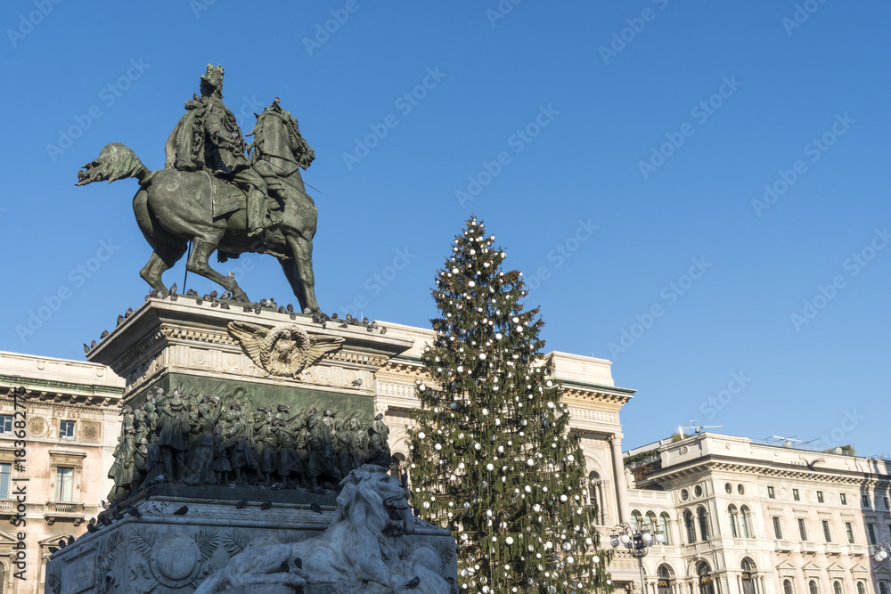 Vittorio Emanuele II statue in Duomo square in Milan, Italy, with Christmas tree in a sunny day of december.