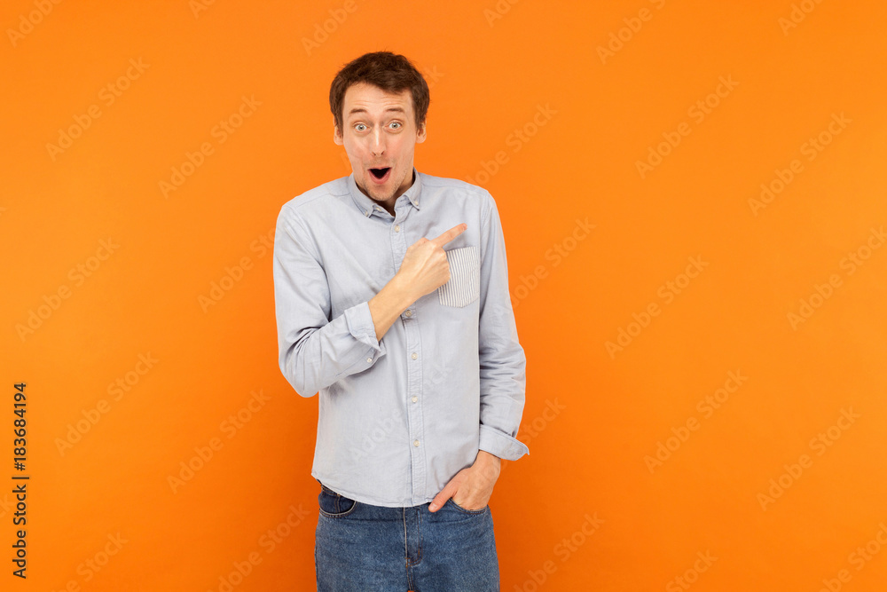 Fototapeta premium Amazement man pointing finger at copy space, open mouth and looking at camera. Have a surprised look .