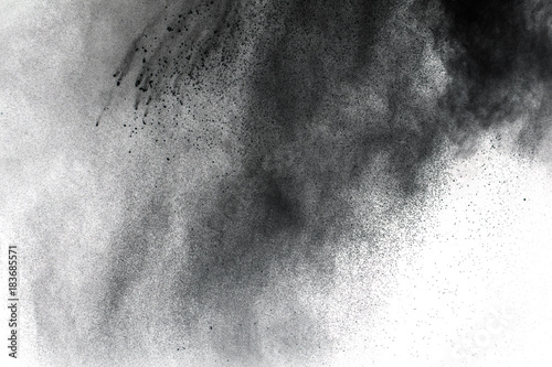Black powder explosion against white background.The particles of charcoal splatted on white background. Closeup of black dust particles explode isolated on white background.