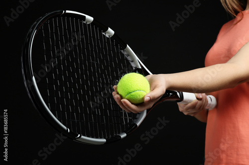 Woman with tennis racket and ball on black background © Africa Studio