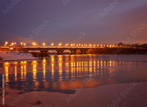 Bridge on the River Dnieper in the evening. Lantern light is reflected in the frozen ice, city © Ryzhkov Oleksandr