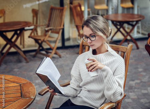 Beautiful young woman reading a book with a cup of coffee