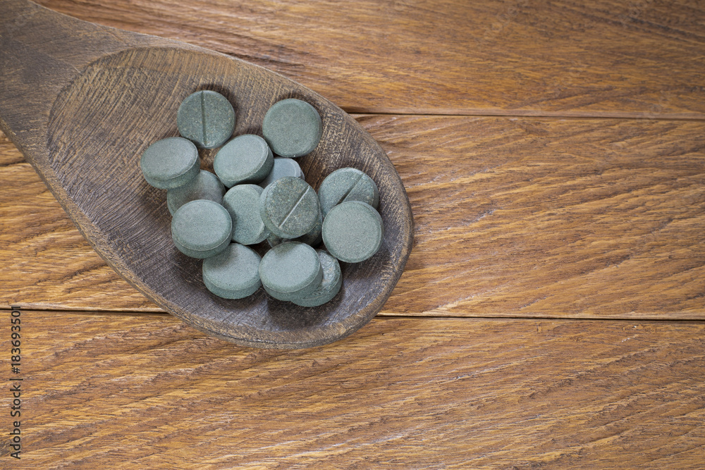 Spirulina tablets in the spoon Spirulina tablets in the spoon