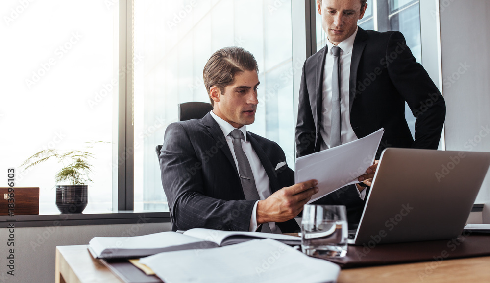 Corporate business people reading papers in office Corporate business people reading papers in office