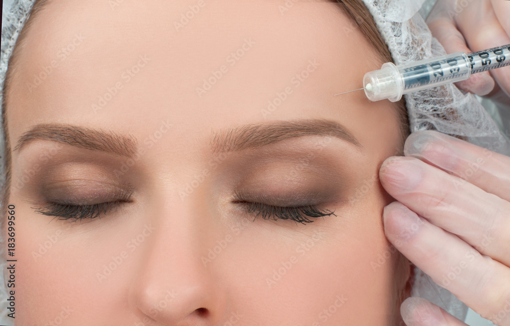 Woman is getting injection over eyebrow. Anti-aging treatment and face lift. Cosmetic Treatment and Plastic Surgery