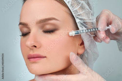 Woman is getting filler injection in cheeks. Anti-aging treatment and face lift. Cosmetic Treatment and Plastic Surgery