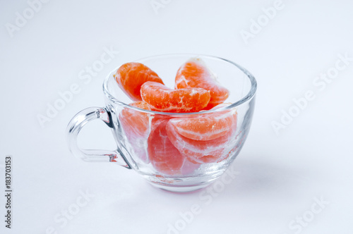 Slices of mandarins in a transparent mug on a light background