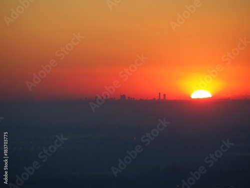 Fiery sunset from the Venetian walls of Bergamo. View of silhouettes of skyscrapers of Milan