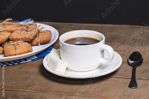 Black coffee in a white cup on a blue napkin and homemade cookies.