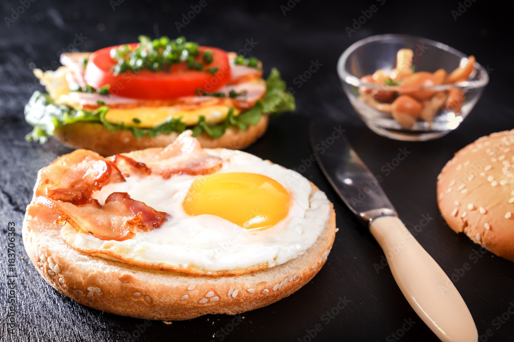 Breakfast with fried egg on bread, bacon, mushrooms, tomatoes and greens. Black background Breakfast with fried egg on bread, bacon, mushrooms, tomatoes and greens. Black background