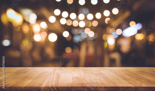 Wood table top with blur of lighting in night street cafe community .celebration concept